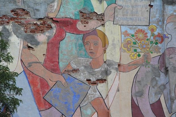 The original brick wall peeks through the faded mural