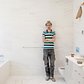 Here the artist leans against the wall of a master bathroom. Behind the tiles, lies a self-portrait, he helped tile over himself.