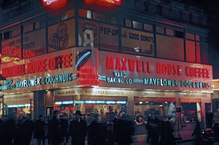 The neon-illuminated Maxwell House and Mayflower Doughnuts coffee shop at the north-west corner of the busy intersection of West 42th Street (which runs left to right) and Broadway 1946