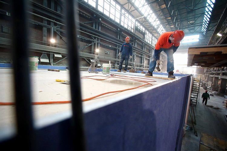 Workers apply a layer of structural cement board and a layer of gypsum board to achieve the required fire rating.