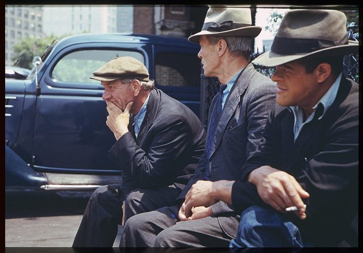 Three men sit on a bench in Battery Park during lunch hour.
