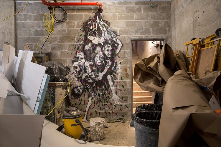 After hours and during lunch breaks, he painted intricate murals in the stairwells, crafted sculptures out of concrete, and transformed trash containers into artistic statements. Here, a mural of tortured faces drips from an exposed pipe.