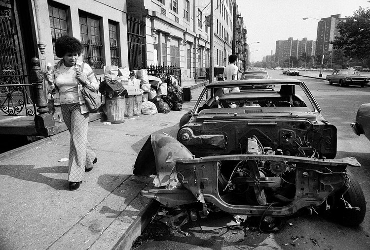A pedestrian looking at a stripped car in the East Village on Oct. 14, 1979.