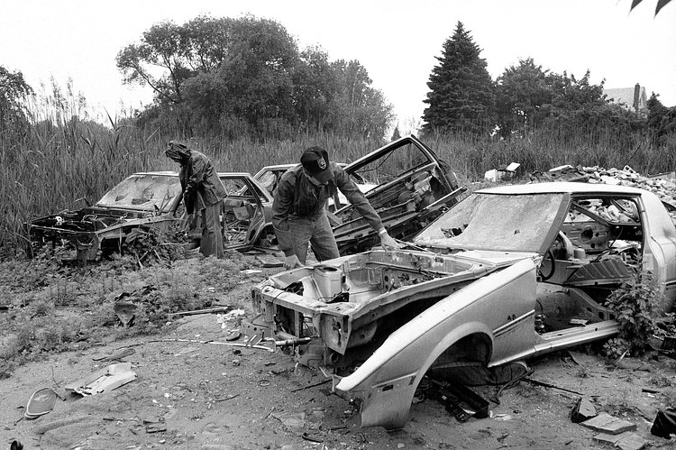 Police officers viewing abandoned cars on the Queens-Nassau border. June 5, 1985.