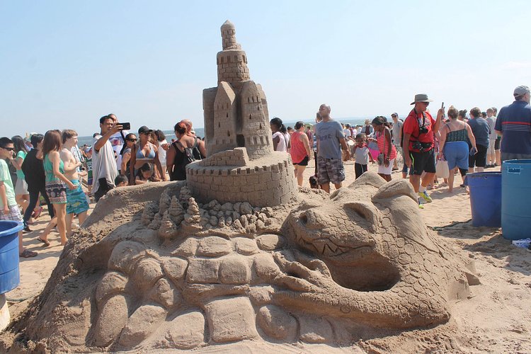 A fearsome dragon appears to be protecting (Or ready to swallow) this sand castle.