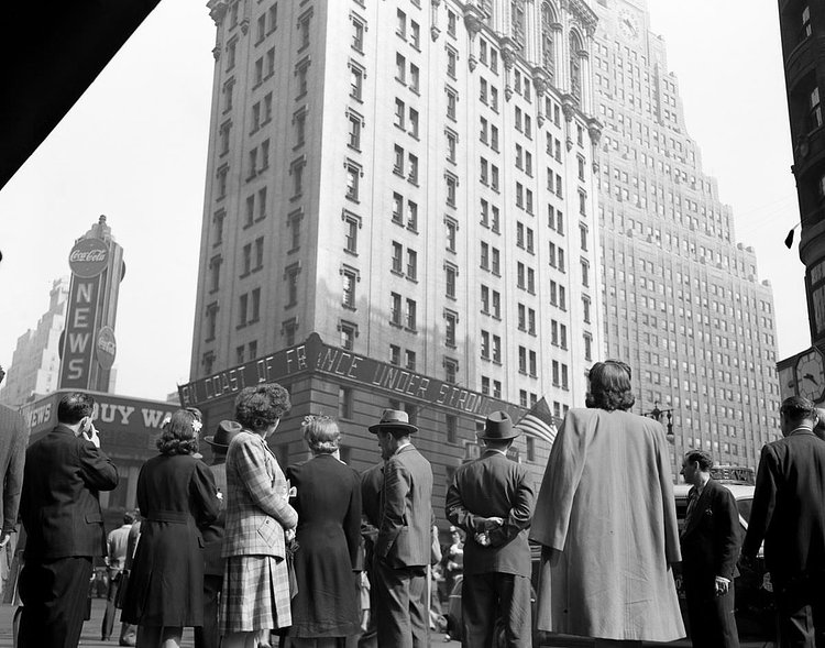 People in Times Square watch the news ticker on the New York Times building