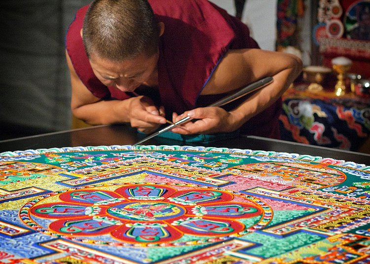 Tibetan monk adding sand to a mandala