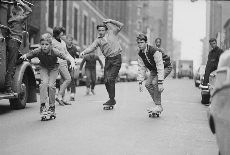 A group of boys skate down a street that probably hasn’t been paved since.