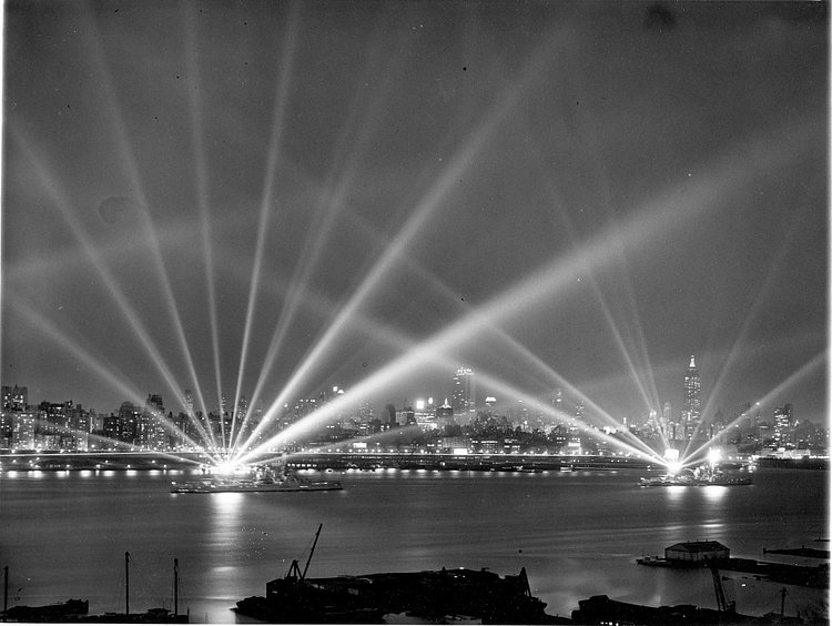 Battleships USS Texas and USS New York on the Hudson light up the night sky with their huge searchlights in search of imaginary aerial attackers. New York, 3 May 1939.