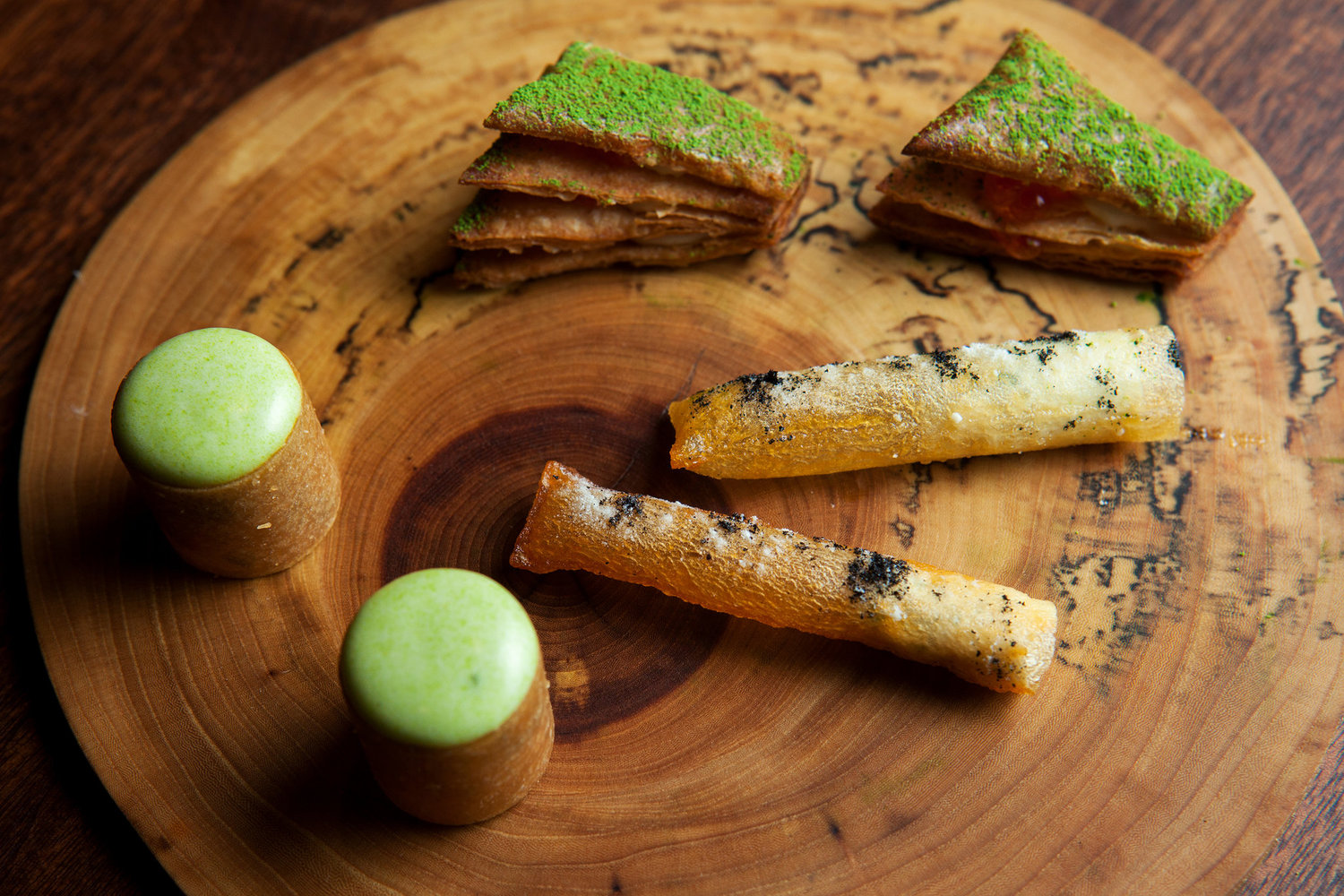 Momofuku Ko moved to an alleyway off East First Street earlier this year. One-bite mille-feuille, whose crisp layers of rye pastry sprinkled with green tea powder hold lush béchamel and briny little globes of trout roe, are shown with pommes soufflé and lobster paloise.