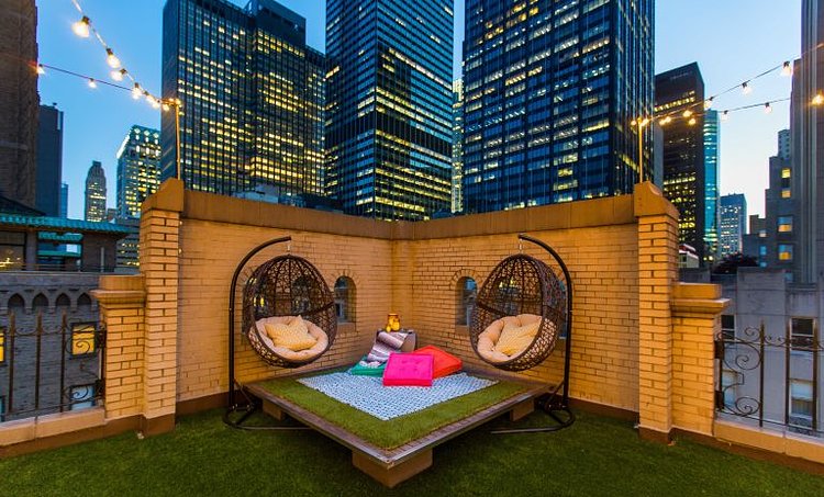 Outside, the entire deck has been covered with a soy-based artificial grass, and there are hanging cocoon chairs and couches draped with bright throws and pillows in a kaleidoscope of colors.