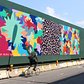 A biker rides by a mural by artist Hisham Akira Bharoocha on Dean Street.