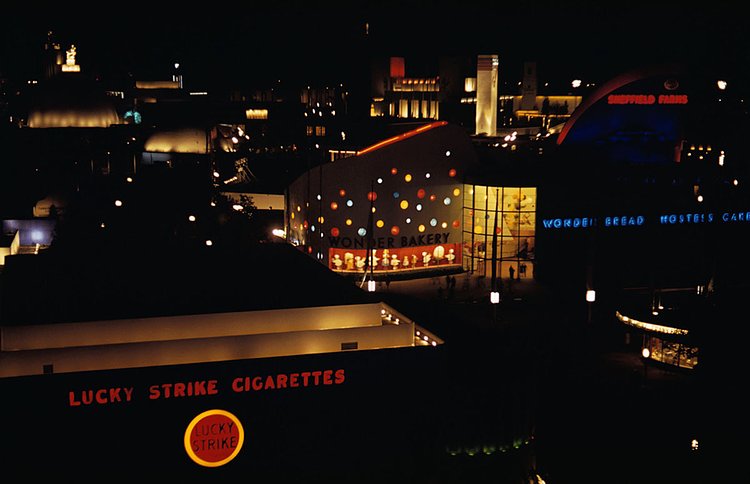 The Lucky Strike Cigarettes and Wonder Bread Bakery buildings are shown illuminated at night at the 1939 New York World's Fair.