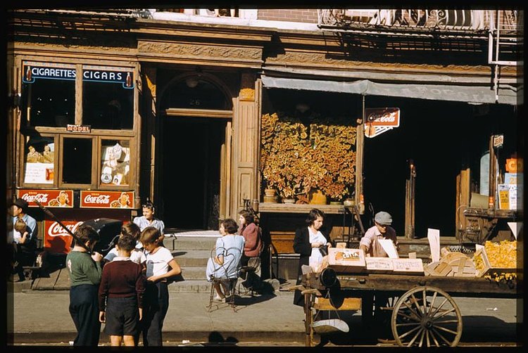 Children and adults gather outside various storefronts near the corner of Broome Street and Baruch Place on the Lower East Side.