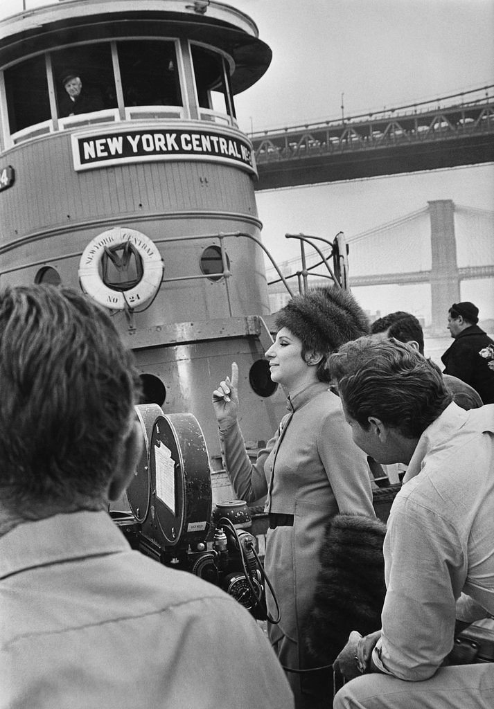 July 18, 1967: “Boy am I gonna sue you. My back hurts. My feet hurt,” Barbra Streisand, the actress and diva, told Ray Stark, the producer of the film version of “Funny Girl,” which was being shot on the East River pier. A story cataloged the actress’s laments as the filmmakers shot take after take of her running down the pier with luggage: “This is the hardest work I’ve ever known. I had to be up at 6 in the morning. I’m not used to that. Normally I don’t get up until 1. I’m used to theater hours,” she said, adding, after picking at her finger, “I got thorns from those damned roses.”