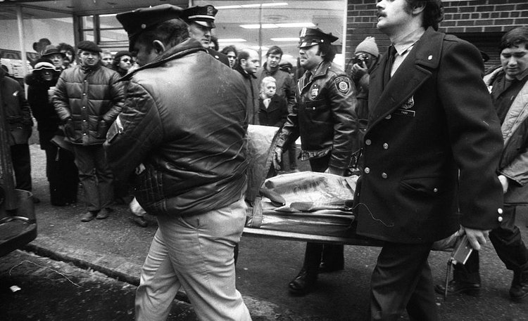 1970's: A body is covered and carried away after a patrolman was killed during a shooting at the 8th St. subway station in 1975.