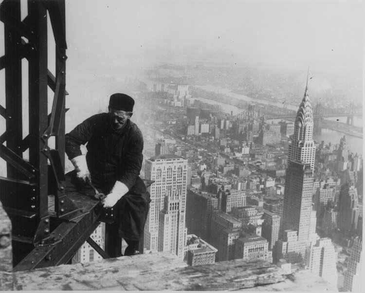 Workman, perched on the end of a beam, bolting together the framework of the Empire State Building, New York City, 1930. Photograph by Lewis Hine