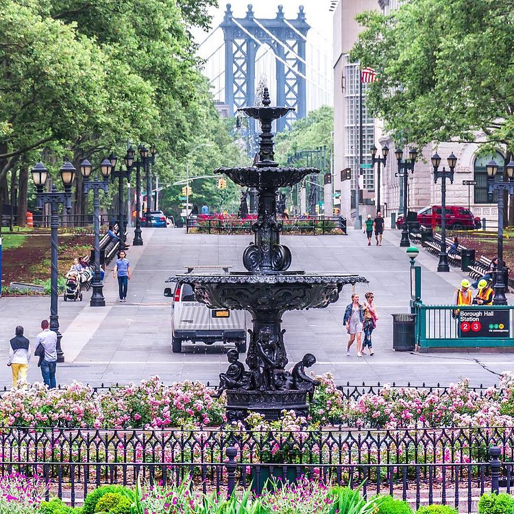 Columbus Park in downtown Brooklyn. Named after Christopher Columbus, the park is one of the the city's first major urban parks that continues to be a gathering place for people of different cultures and ages, and hosts a wide variety of events and assemblies. Behind the fountain is part of the Manhattan Bridge. Downtown Brooklyn, New York City.