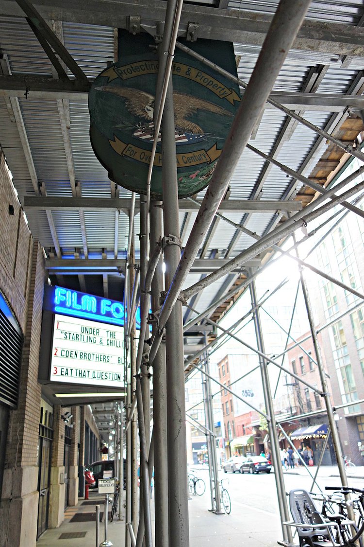 The United Alarm Systems sign, which covers the frame of an old neon sign, sticking out from the scaffolding