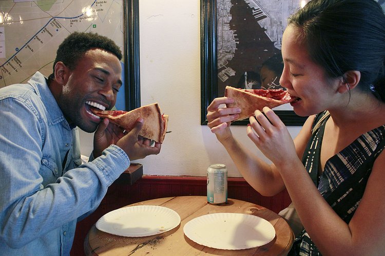 Man and Woman Eating Folded Slices of Pizza and Smiling | You can use this photo for non-commercial purposes if you give credit, under this <a href="https://creativecommons.org/licenses/by-nc/3.0/us/" rel="nofollow">Creative Commons license</a>. For-profit media organizations also may use this, but as editorial content only (as illustrations for stories, for example, but not as advertising). Credit must read: Louise Ma / WNYC

We'd love to know if you're using this photo - send us an email (jkeefe@wnyc.org)!
