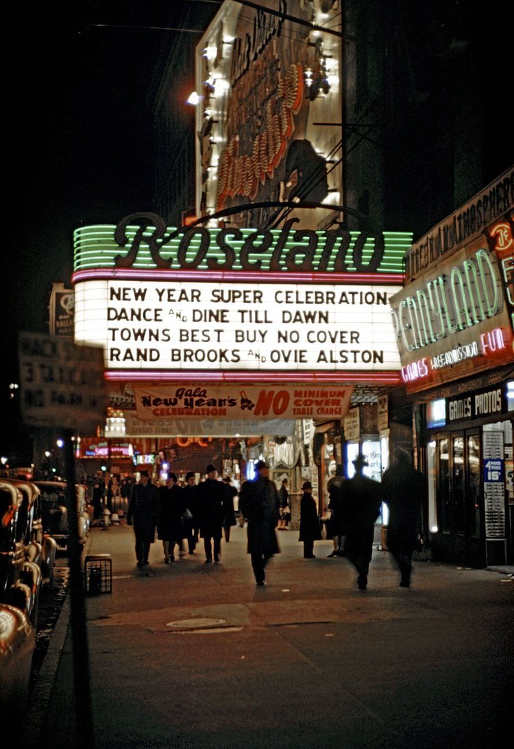 Pedestrians pass under the neon-lit marquee of the Roseland Ballroom (1658 Broadway). The marquee advertises a ‘New Year Super Celebration.’ The venue moved to a new location in 1956