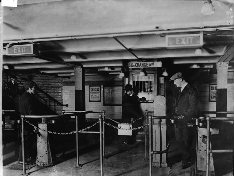 A man gets change in nickels from a change booth operator so he can pass through the new nickel-operated turnstiles which have replaced the ticket and ticket-chopper (a man who manually cut tickets at the gate) system in the New York City subway, early 1920s. The move allowed subway companies to reduce operating costs by drastically reducing personnel.