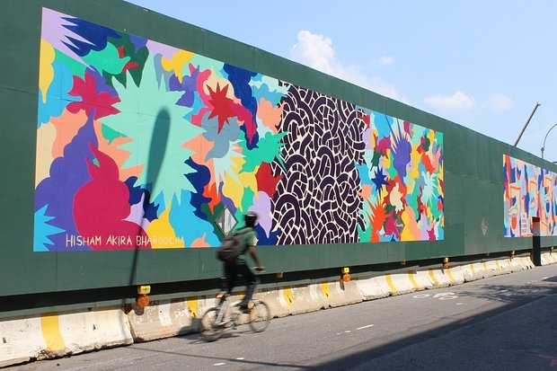 A biker rides by a mural by artist Hisham Akira Bharoocha on Dean Street.