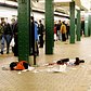 1990's: Subway riders walk by a horrific crime scene on the platform of the 125 St. station after an unidentified person was shot, leaving behind a pool of blood and clothing of the victim.