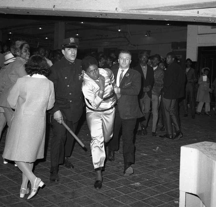 1960's: Police officers escort a member of a mob of disorderly youths away from the subway station at Stillwell Avenue in Coney Island. 