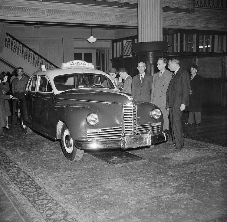 G.H. Brodie, Assistant to the President of Packard Motor Car Co.; Sam Abramson, President of Yale Taxi Co. in New York; and Robert King, President of Packard Federal Corp. (left to right), pictured with the first postwar taxi, in 1946. One of its features was fitting five forward-facing passengers without the usual "jump seats."