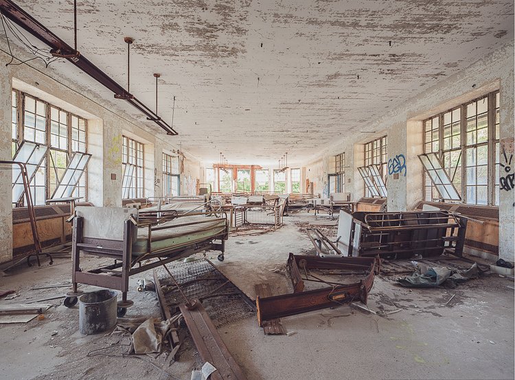 Hospital beds, cribs, and equipment left behind in a day room on a lower floor.