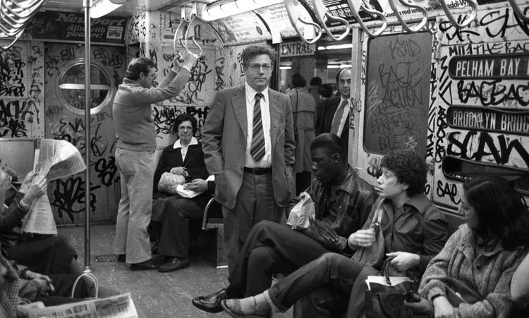1980's: A man wearing a crisp business suit pops against this subway car scrawled over with heavy graffiti.