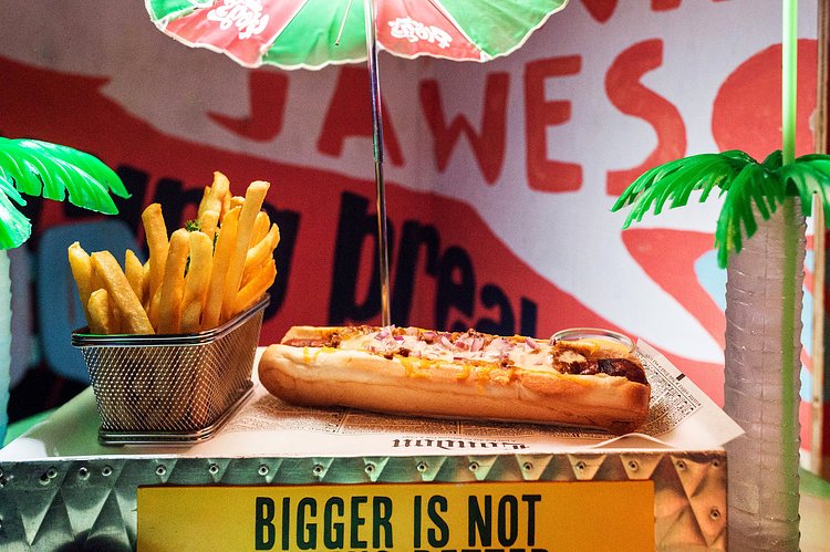 A chili dog served on a hot-dog cart.