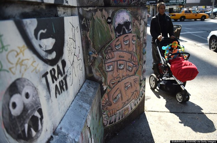 People walk by street graffti in New York on April 25, 2014.