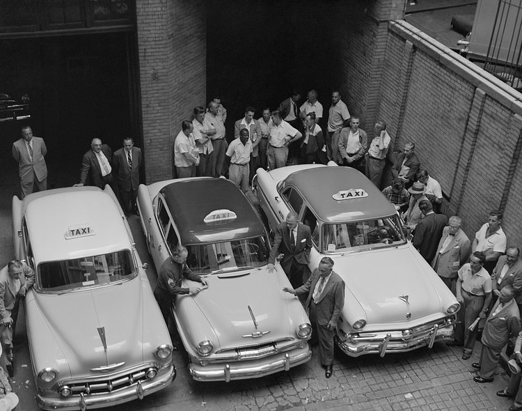Representative models of the three makes of autos which meet the new specifications for service as New York taxi cabs get a going-over by officials at the Police Division of Licenses Headquarters, July 15, 1954. Left to right, the new stock model small taxis expected to be on the streets by July 16th are: A Chevrolet, a Plymouth, and a Ford.