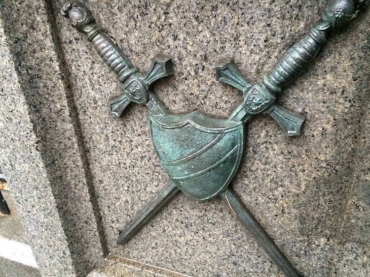 One of the bronze relief images, crossed swords and shield