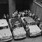 Representative models of the three makes of autos which meet the new specifications for service as New York taxi cabs get a going-over by officials at the Police Division of Licenses Headquarters, July 15, 1954. Left to right, the new stock model small taxis expected to be on the streets by July 16th are: A Chevrolet, a Plymouth, and a Ford.