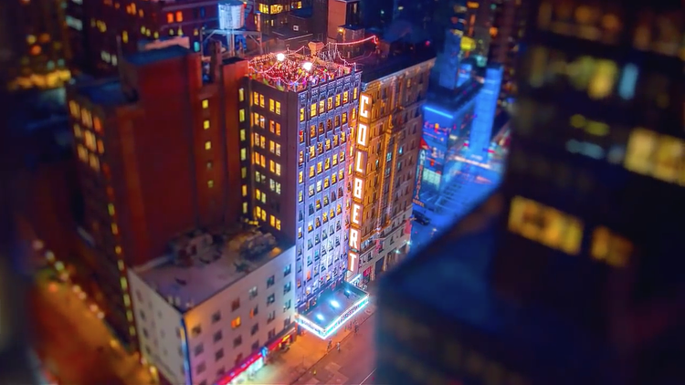 Finally, the home of The Late Show with Stephen Colbert, the Ed Sullivan Theater, is pictured. Located at 1697–1699 Broadway, CBS has used the 400-seat venue for broadcasts since 1936. A party on the rooftop of the brick-clad building is visible alongside a vertical glittering 'COLBERT' sign. 