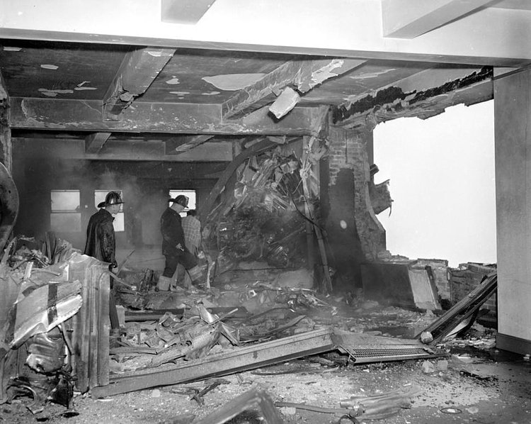 B-25 Mitchell bomber smashed beyond recognition into Empire State Building. This is a picture of the wreckage-strewn 79th floor where the bomber tore a 18-foot hole in wall. Propeller is embeded in the wall at the left.