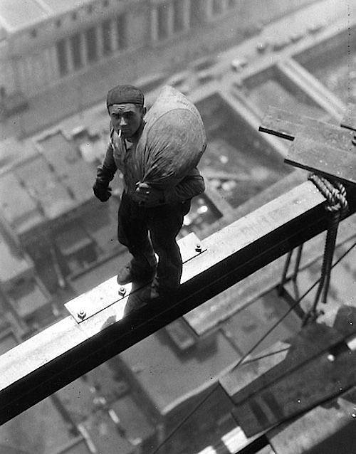A construction worker on a beam high above the building at Wall Street, New York City, 1930.