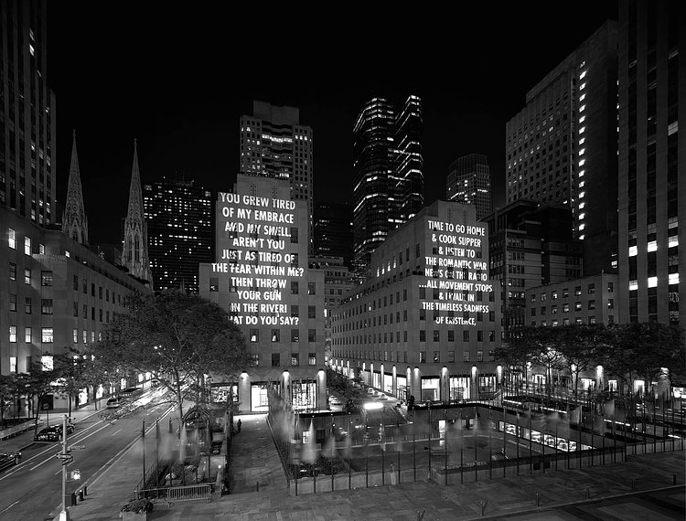 Rockefeller Center lit up by Holzer’s projections in 2005. The words on the left are an excerpt from the poem “He Embraces His Murder” by Mahmoud Darwish. The words on the right are an excerpt from the poem “My Sad Self” by Allen Ginsberg.