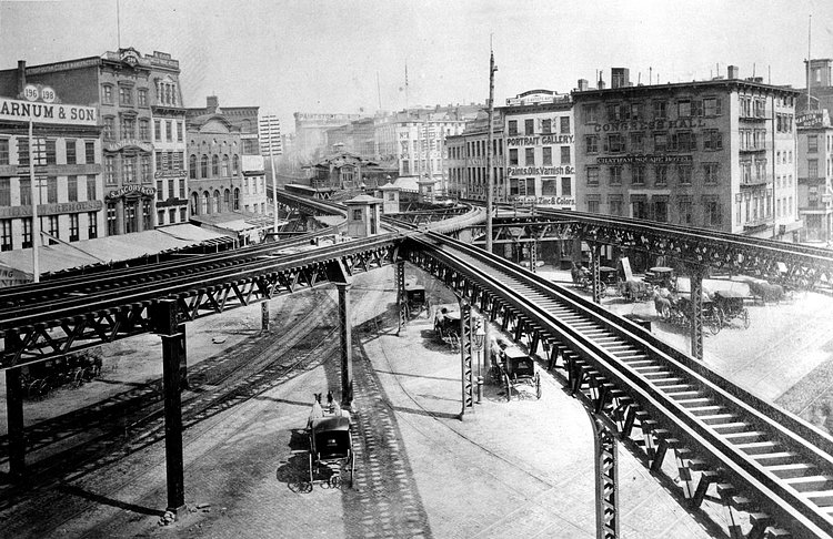 This is an 1878 view of the Third Avenue Line El train tracks, looking north up the east side of the Bowery, at Chatham Square in lower Manhattan, New York.
